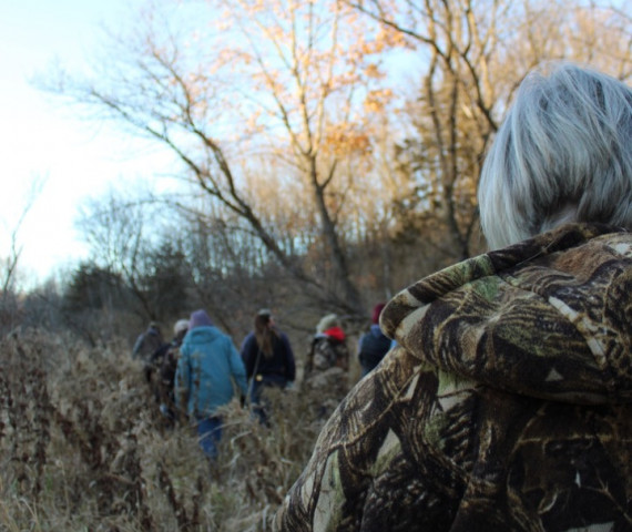 A view over the shoulder of a group of women walking through a woodland