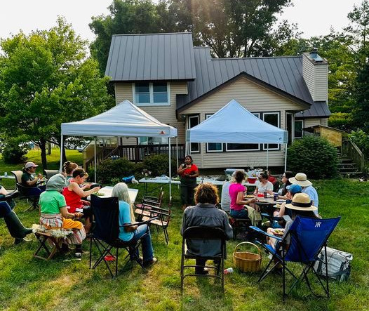 people sit in lawn chairs in a backyard while someone presents a talk